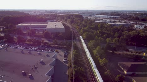 drone shot following train at a steady speed, an industrial area with an almost full parking lot