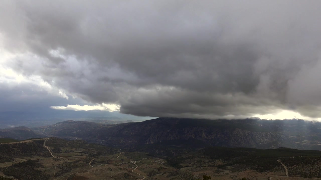 Nuvole temporalesche scure che si addensano su paesaggio montano