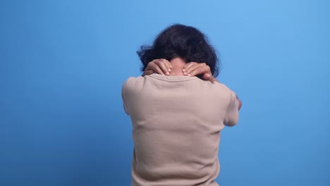 back view of an elderly asian woman gives herself a neck massage, pain in the cervical vertebrae