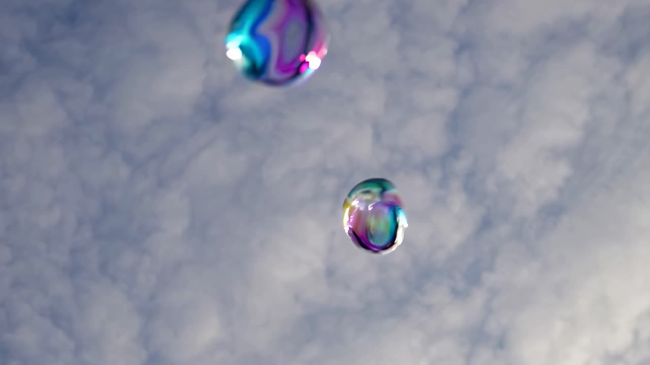 Video sudut rendah balon warna-warni yang mengambang di langit berawan, menangkap kesan jenaka.