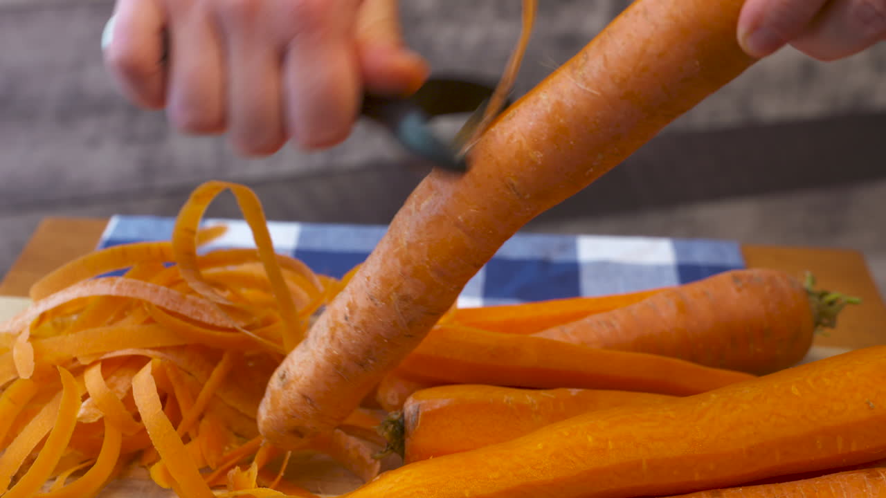 Preparazione in cucina, sbucciare un mazzo di carote.