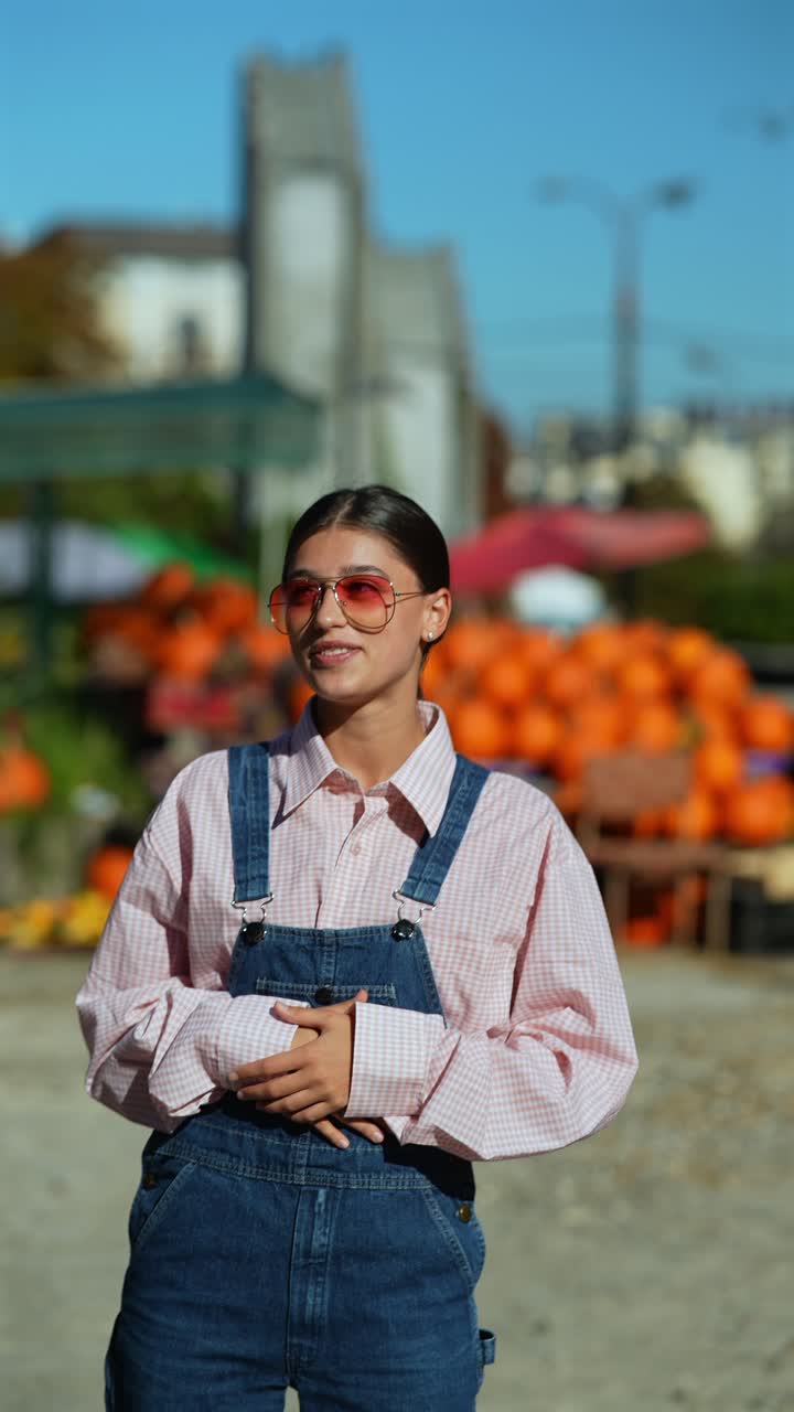 mujer joven en mono y gafas de sol en un parche de calabaza