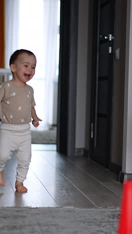 happy caucasian boy runs into the room cheerfully. little kid goes past the toys on the floor. vertical video