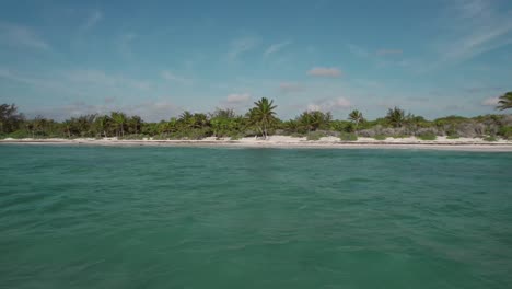 Tropical-beach-aerial-reverse-low-level-view-over-calm-seas-Xpu-Ha,-Mexico