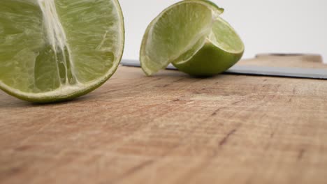 sliced limes on wooden board with knife