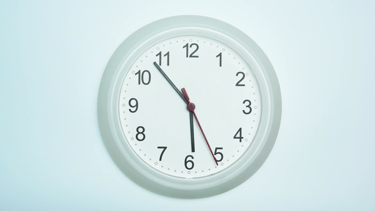 el reloj de pared blanco muestra la hora de cinco minutos a las seis.