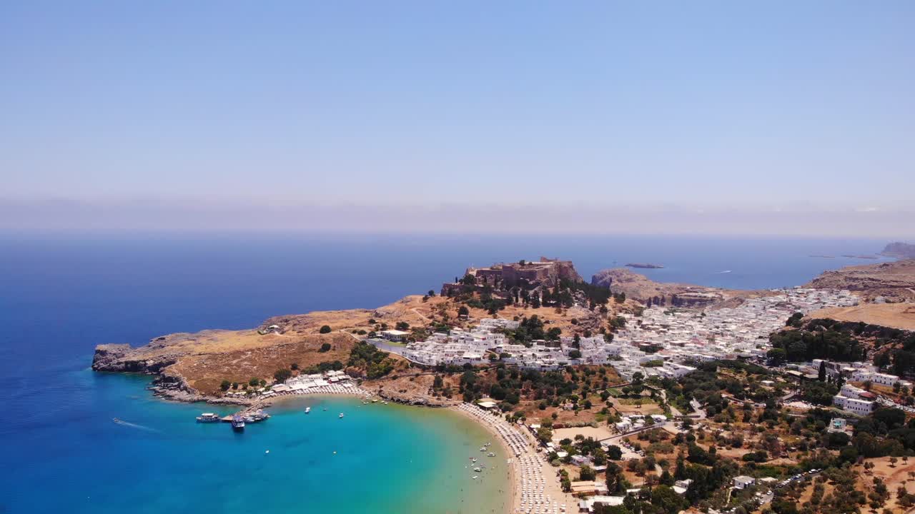 그리스의 흰색 주택과 아름다운 해변이 있는 린도스 마을의 탁 트인 전망 - 공중 드론 샷