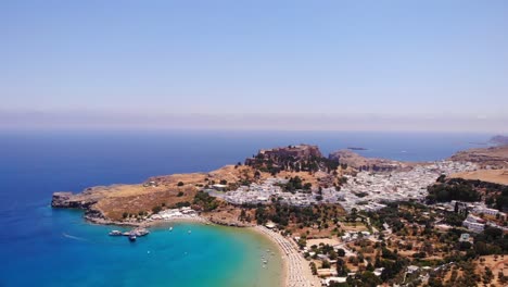 panoramic view of lindos town with white colored houses and scenic beach in greece - aerial drone shot