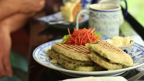 Picky-eater,-having-vegan-panini-and-coffee-for-breakfast-but-picking-off-only-the-coconut-cream