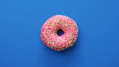 sabrosas rosquillas cubiertas de esmaltes de chocolate rosado aisladas en azul, filmadas con la cámara de cine red raven 4k