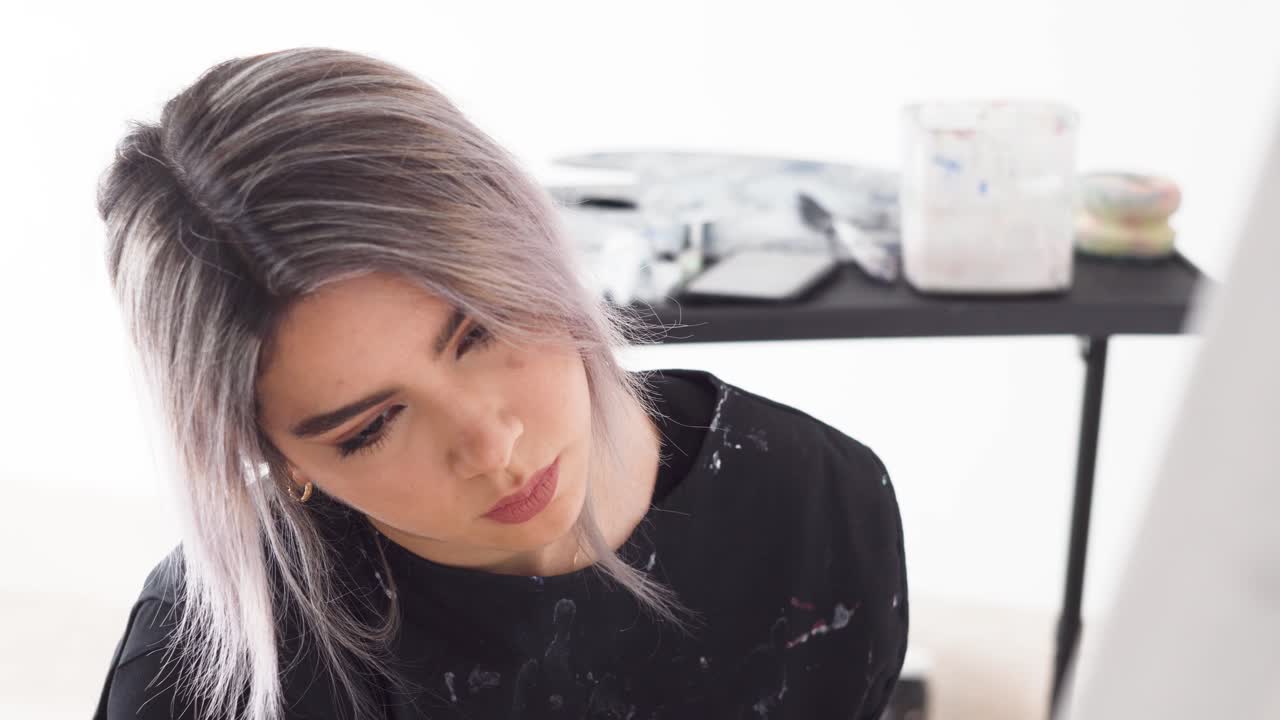 흰색 아크릴 페인트로 그녀의 캔버스를 코팅하는 팔레트 나이프를 가진 사랑스러운 화가의 초상화