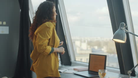 woman using phone, drinking tea and working on laptop in office