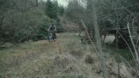 filmmaker cycles within forest with backpack and tripod