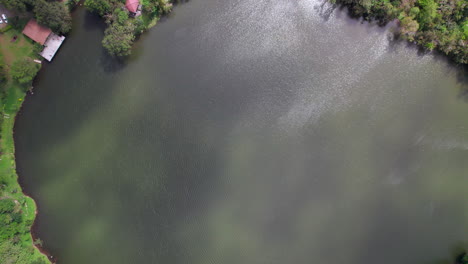 Un-Lago-Sereno-Rodeado-De-Vegetación-Y-Casas-En-San-Carlos,-Luz-Del-Día,-Vista-Aérea