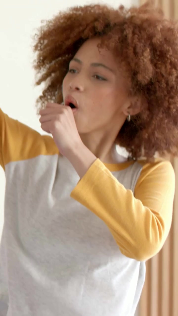 Video verticale: Entra nell'inquadratura, donna con capelli ricci che guida con un microfono, mima e balla a casa.