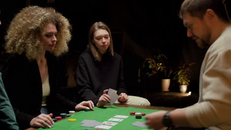 group of friends playing poker sitting on chairs at a table at home 1