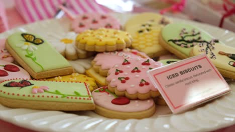 a plate on bakery stall table with beautifully created warm biscuits in many different colours.