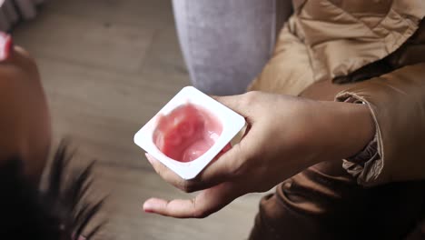 una mujer comiendo yogur de fresa.