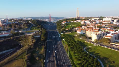 drone parallax shot to the left over a highway facing towards the 25th of april bridge in lisbon with cristo rei in the background