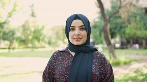 beautiful smiling, confident young woman with a pretty face looking at the camera posing alone outdoors, a happy millennial asian girl student in the veil