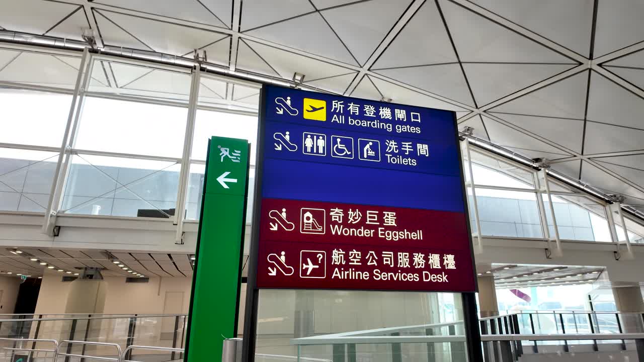 A detailed interior shot of an information board at Hong Kong Airport, showing directions to important facilities like boarding gates and toilets.
