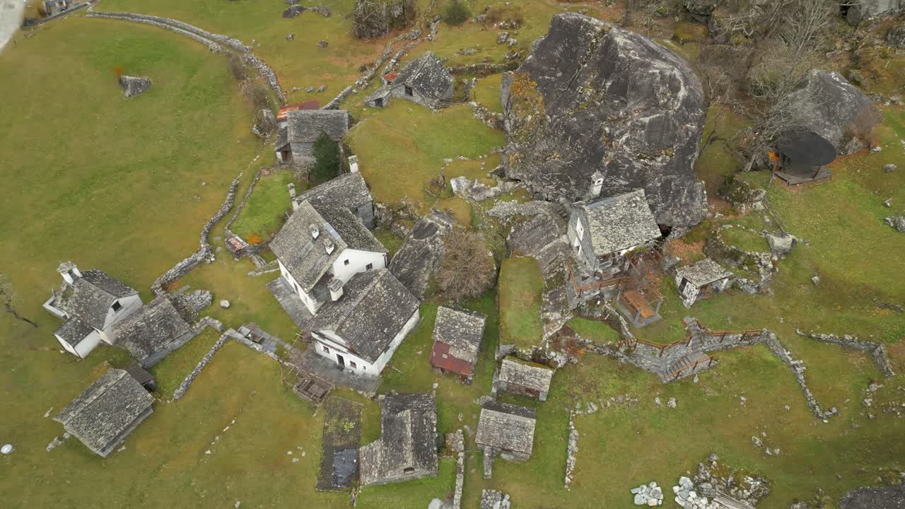 drone aéreo de arriba hacia abajo filmado volando sobre viejas casas vacías de piedra en cavergno, distrito de vallemaggia, cantón de ticino en suiza durante el día