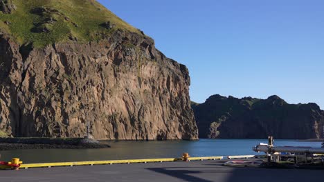 port of vestmannaeyjar, heimaey island, iceland on sunny day, steep cliffs above sea and dock