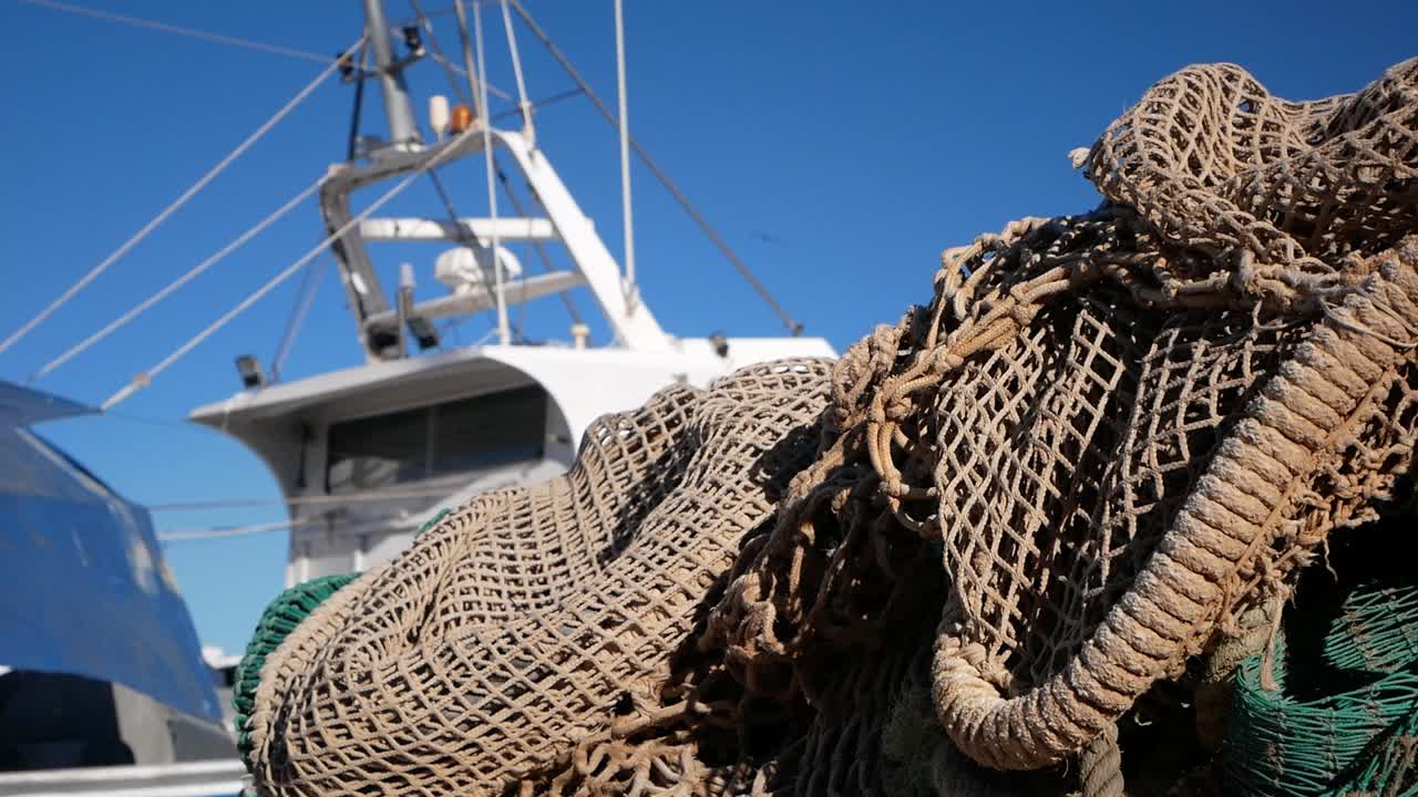 Slow motion approach to a fishing net with a boat in the background