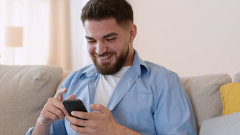 happy young man using smartphone on couch