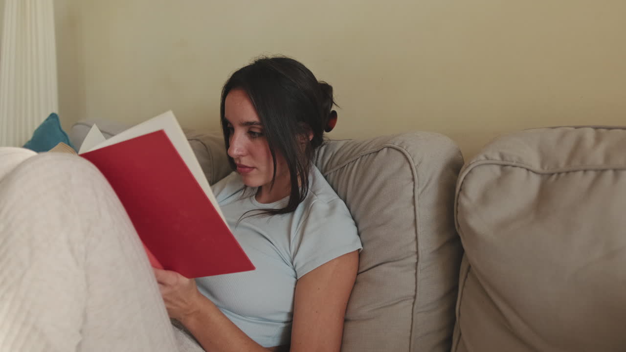 mujer leyendo un libro en un sofá