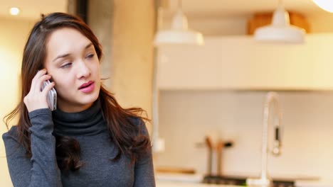 Woman-talking-on-mobile-phone-in-living-room