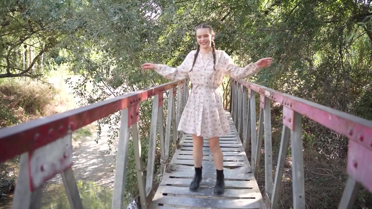 Una donna cammina su un ponte rustico splendidamente circondato da una natura rigogliosa.