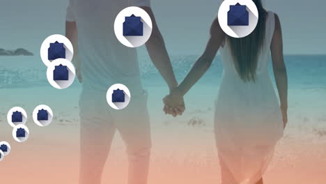 Holding-hands-on-beach,-couple-with-email-icons-animation-over-ocean-background