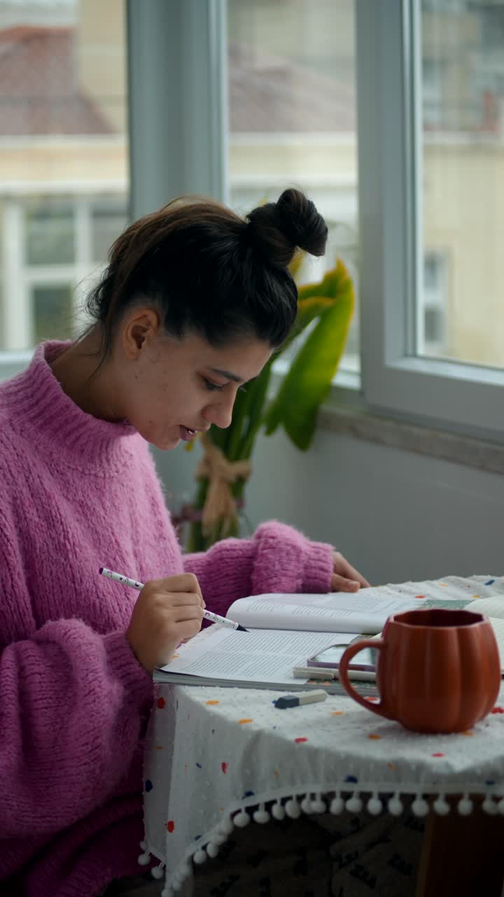 Giovane donna studia e scrive in un libro a casa