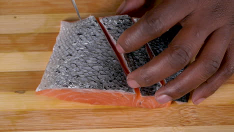 a medium shot from the top of a chef slicing a piece of raw fish on a chopping board in slow motion