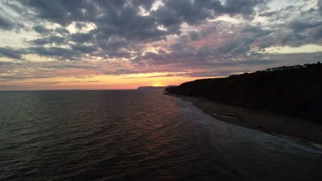 Imágenes-Aéreas-De-Drones-4k-De-Un-Comienzo-Bajo-Y-Un-Ascenso-Hacia-Una-Puesta-De-Sol-Dorada-Frente-A-La-Costa-De-La-Isla-De-Wight