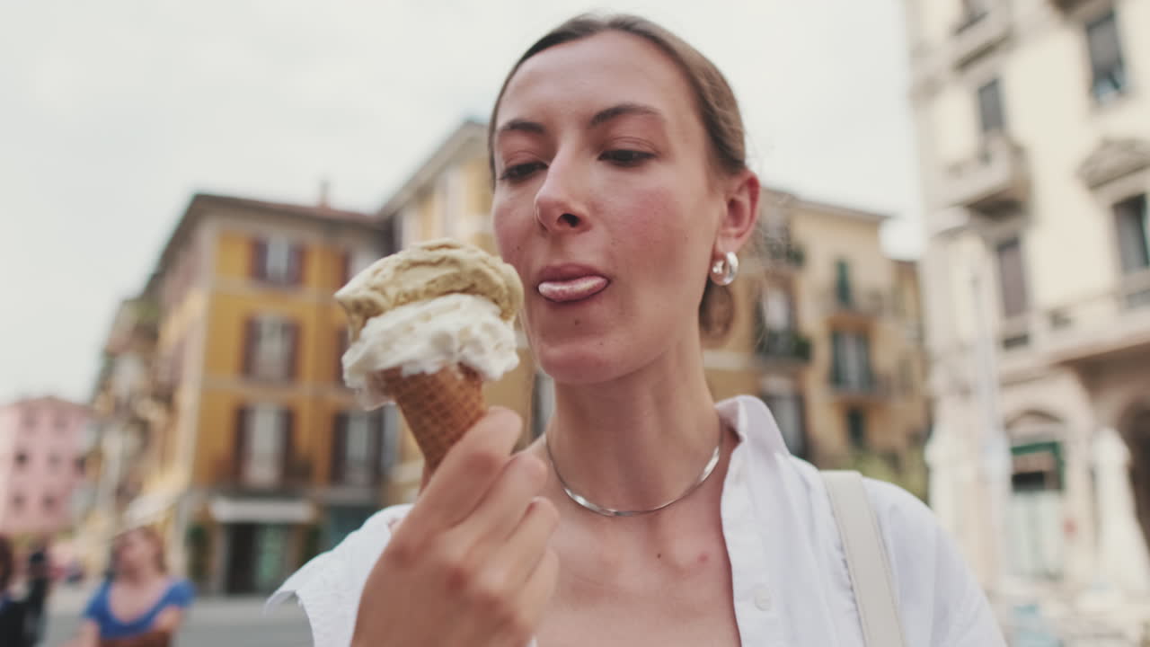 Giovane donna che si gusta un gelato in una via della città