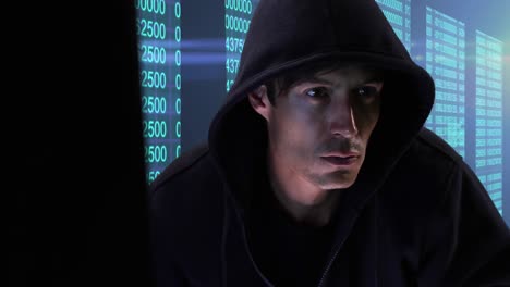 animation of male hacker wearing hoodie, using laptop over multiple screens