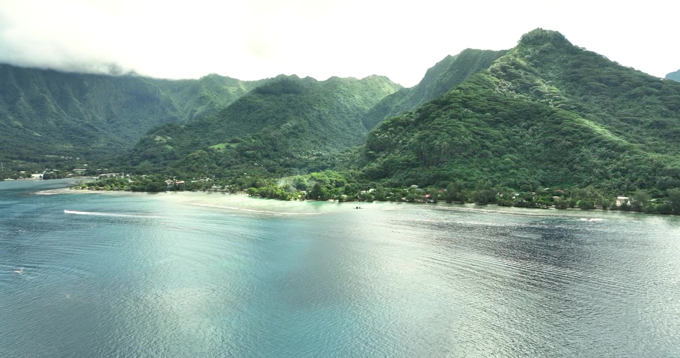 Tropical coastline with green mountains and calm blue water, French Polynesia