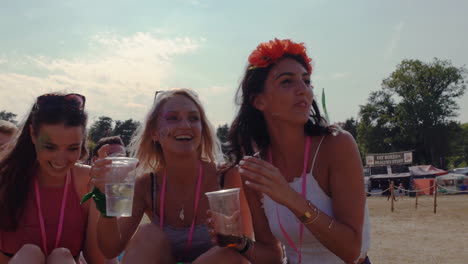 three female friends sitting on grass at a music festival