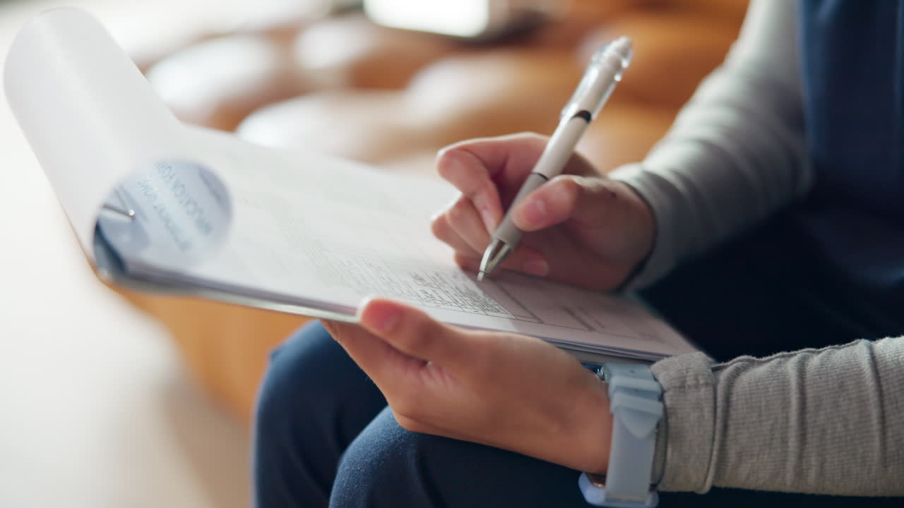 Primo piano di una mano che scrive su un documento con una penna