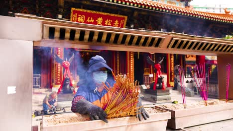 person lighting incense at hong kong temple