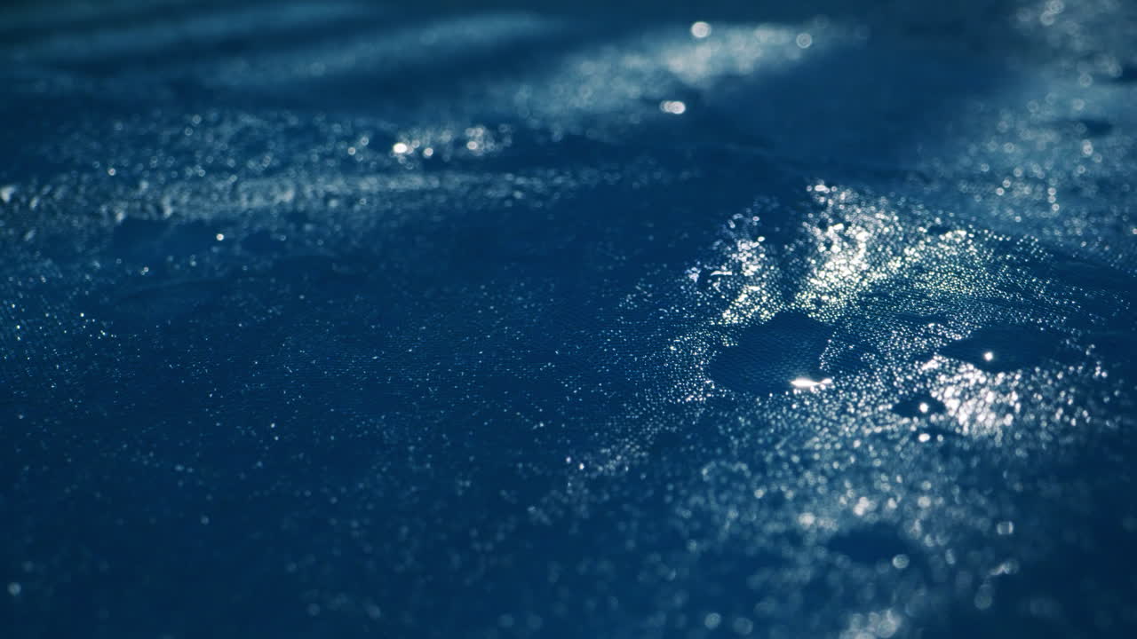 A serene water surface with gentle ripples and glistening raindrops in calming blue hues, creating peace