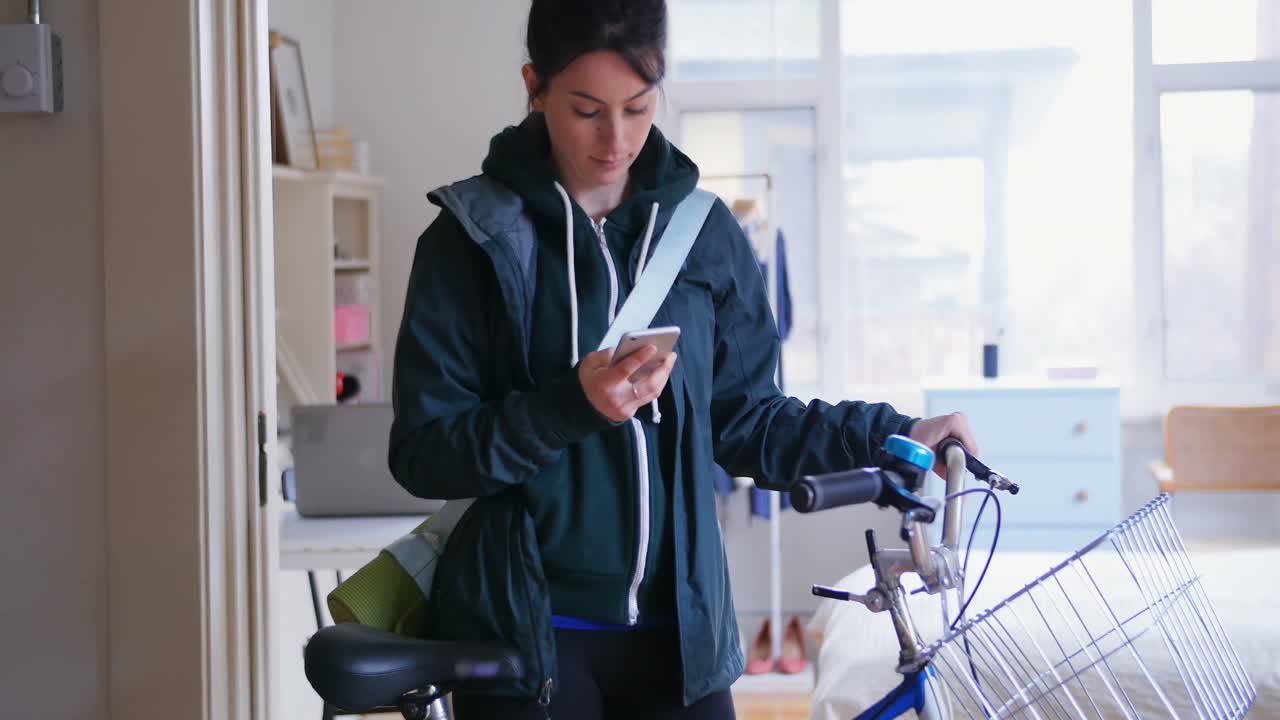 mujer usando su teléfono móvil mientras saca su bicicleta 4k