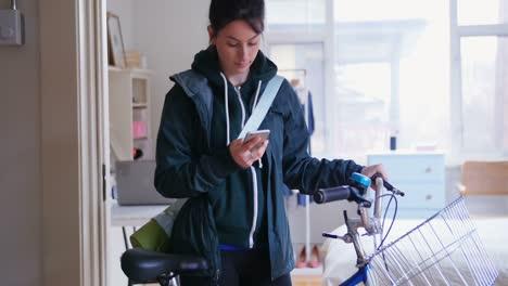 Woman-using-her-mobile-phone-while-taking-her-bicycle-out-4k