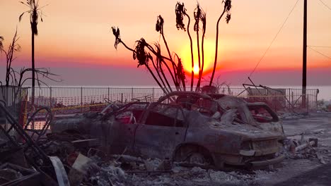 burned cars smolder at sunset beside a hillside house following the 2017 thomas fire in ventura county california