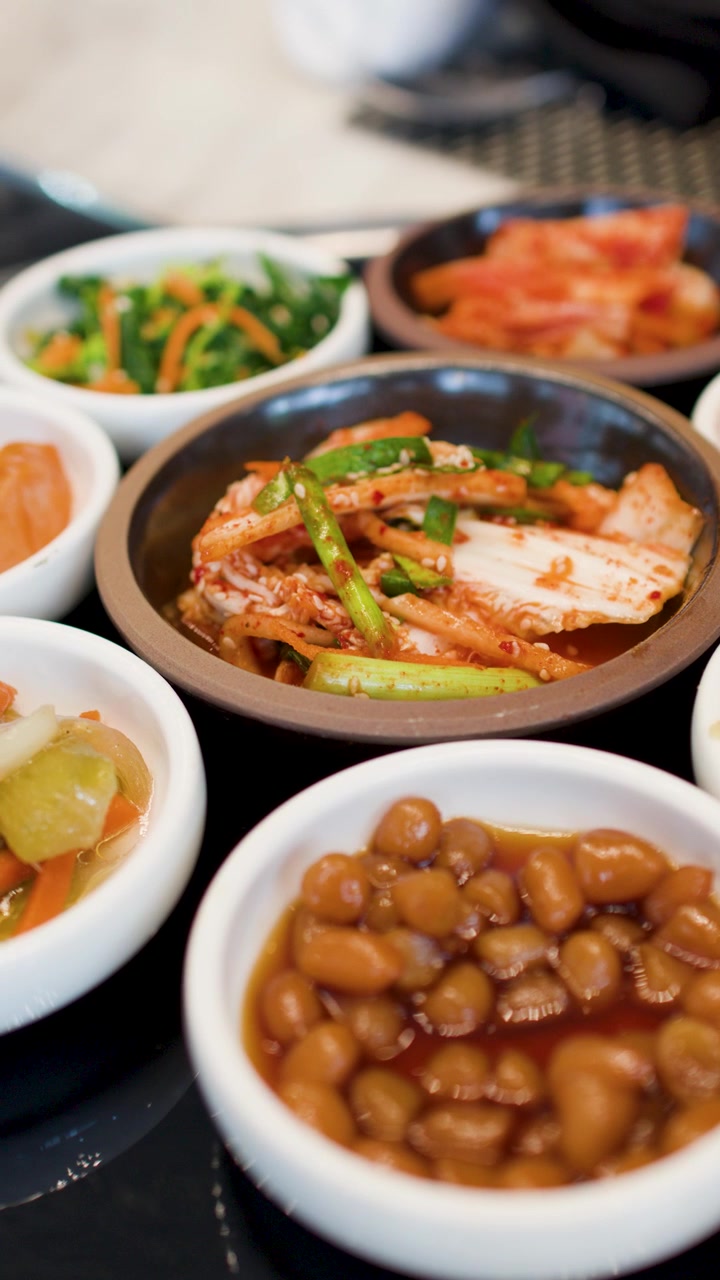 Bidikan jarak dekat hidangan pendamping tradisional Korea di meja restoran dengan pencahayaan alami yang lembut