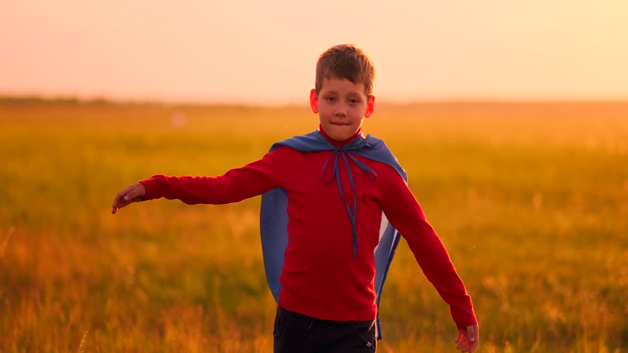 un niño vestido como un superhéroe de pie con una máscara y una capa roja corre riendo de la puesta de sol en el campo de verano. noche de verano el niño sueña y hazañas heroicas y cómics