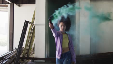 Mixed-race-woman-holding-green-flare-walking-through-an-empty-building