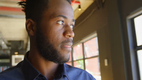 Front-view-of-happy-young-black-businessman-looking-at-camera-in-a-modern-office-4k